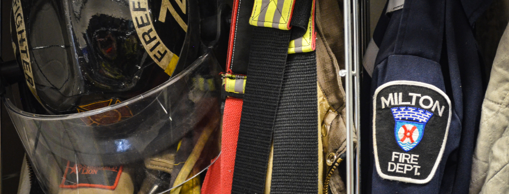 A Milton Fire Department helmet and a coat with a Milton Fire Department patch