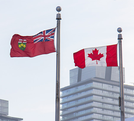A Canadian flag and Ontario flag flying side-by-side